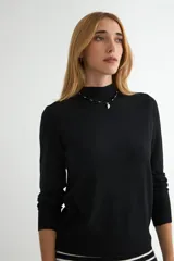 Polera de punto color beige, con cuello alto y mangas largas, de diseño básico y ajuste clásico.