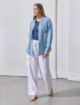 Camisa celeste de tencel, marca Hester & Orchand. Tiene cuello con solapa, escote en V, abertura central con botones, bolsillo aplicado en el frente y ruedo desflecado.