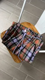 Pantalón sastrero de corte recto y tiro alto, con estampa escocesa en tonos verde, naranja, lila y negro. Cuenta con cintura elástica ajustable con cordón y bolsillos laterales.