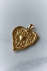 Collar con dije de corazón en acero quirúrgico, con textura irregular y relieve, montado sobre un tiento encerado negro.