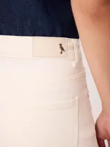 Short de denim elastizado de tiro alto, color beige, con bolsillos delanteros y traseros, y cierre frontal con botón y cremallera.
