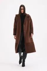 Tapado largo de gamuza color chocolate con detalles de corderito en solapas, puños y ruedo. Presenta cierre frontal con botones y corte recto.