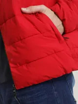 Campera puffer roja Calvin Klein, con cuello alto, cierre frontal con cremallera, bolsillos laterales con cierre, puños elásticos y logo en la manga.