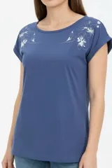 Remera de algodón negra, de corte holgado, con cuello redondo a la base y detalle de estampado floral en el hombro izquierdo.