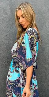 Vestido midi de seda con estampado paisley en tonos turquesa, azul marino, rosa y amarillo. Cuenta con mangas cortas fluidas y diseño amplio.
