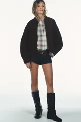 Cazadora tipo bomber de Zara confeccionada en piel de ante 100%. Presenta cuello redondo, cierre frontal con cremallera metálica, bolsillos delanteros con solapa y bajo con acabado elástico.