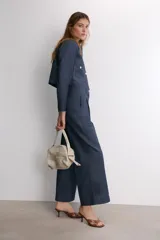 Pantalón de tiro medio confeccionado en denim azul oscuro, con diseño de pierna ancha, pinzas frontales y pespuntes a contraste. Cuenta con cierre frontal de cremallera y botón.