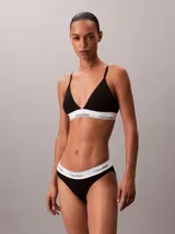 Bralette de triángulo Calvin Klein confeccionado en una mezcla de algodón, modal y elastano. Presenta copas ligeramente forradas sin aro, tirantes ajustables y la icónica banda elástica con el logo de la marca.