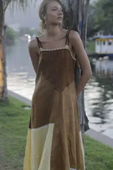 Vestido midi de lino color salmón, de corte amplio y silueta holgada. Presenta diseño con cortes irregulares y detalles de pasamanería en el escote y costuras. Cuenta con breteles dobles tipo cuerda y ruedo asimétrico.