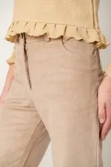 Polera de manga larga color beige con textura acanalada, cuello redondo y detalle de volados en el ruedo y los puños.