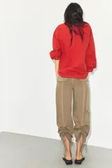 Pantalón de tiro medio confeccionado en tejido fluido color tostado. Presenta bolsillos de plastrón en el delantero y en la pierna, solapas en la espalda y detalle de frunces ajustables en el bajo. Cierre frontal con cremallera y botón.