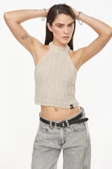 Top de punto estilo halter, color crudo, con cuello alto ajustado, diseño sin mangas y corte corto.