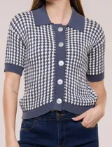 Cardigan de punto con patrón geométrico bicolor en gris y blanco, de manga corta, cuello polo y cierre frontal con botones nacarados.
