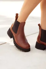 Botas Chelsea de cuero color marrón, con elástico lateral negro y suela track negra gruesa. Presentan un detalle texturado en el talón.