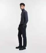 Buzo de corte slim, color negro, con cuello alto y mangas largas, confeccionado en tejido de punto liso.