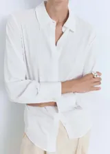 Camisa de corte recto y tejido fluido, con cuello camisero, cierre frontal de botones y mangas largas con puños abotonados.