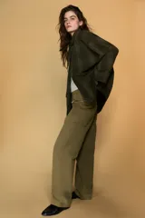 Chaqueta de algodón encerado con diseño de cuadros en tonos verde oliva, beige y líneas rojas. Presenta cuello solapa, cierre frontal con botones a presión metálicos, bolsillos de plastrón con solapa y un detalle de pañuelo desmontable sobre los hombros.