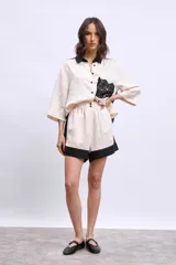 Camisa color crudo con cuello negro, mangas 3/4 y aplique de crochet negro en el frente.