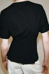 Camiseta de algodón con cuello redondo y manga corta. Presenta un diseño entallado con pinzas en la cintura y bajo recto.