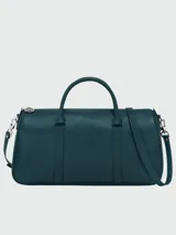 Bolso tipo shoulder bag de diseño minimalista y estructurado, confeccionado en cuero liso color azul petróleo. Cuenta con doble asa superior, correa de hombro ajustable y extraíble, y cierre superior con cremallera.
