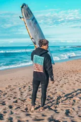 Hoodie negro de corte oversize, con capucha y un gran estampado gráfico en la espalda con marco turquesa y fondo degradado en tonos naranjas y amarillos.