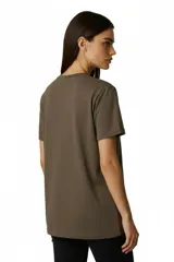 Remera de algodón color marrón topo, de corte al cuerpo y cuello a la base. Presenta un estampado frontal con diseño artístico de una figura humana con detalles en glitter.