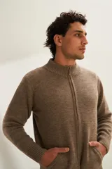 Campera tejida color marrón claro con cierre delantero, cuello alto y bolsillos delanteros. Tejida en 100% lana fina sin teñir.