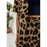 Conjunto de dos piezas compuesto por una camisa de manga corta con cuello italiano y cierre frontal de botones, y un short con cintura elástica y bolsillos laterales. Ambas prendas presentan un diseño estampado de animal print.