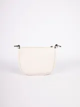 Cartera bandolera color crema de símil cuero, con apliques frontales de tachas redondas de colores y estrellas plateadas. Tiene correa regulable con hebillas y cierre superior con cremallera.