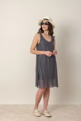 Vestido corto de seda color gris oscuro, con escote redondo y tirantes anudados en los hombros. El calce es suelto y la tela es ligeramente transparente.