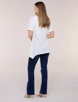 Blusa blanca de tejido de punto liviano con textura labrada en franjas verticales y caladas, de silueta evasé, con escote redondo, manga corta y ruedo asimétrico en picos.