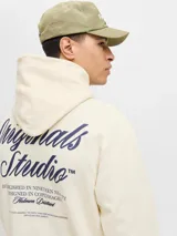 Buzo con capucha de calce holgado, color crema, confeccionado en tejido loopback con interior levemente afelpado. Presenta bolsillo frontal tipo canguro, puños y ruedo acanalados, y estampado con texto en el pecho.