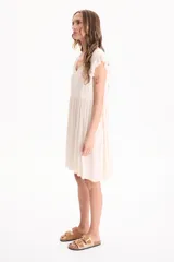 Vestido corto de viscosa color beige, sin mangas con volados en las sisas, escote en V y diseño escalonado.