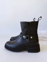 Bota corta negra de cuero, con caña media, hebilla lateral y suela track.