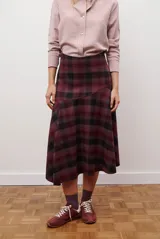 Falda midi de corte irregular con diseño a cuadros en tonos marrones, negros y beige. Presenta una silueta acampanada con caída fluida.