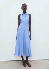 Vestido midi celeste a rayas verticales, sin mangas, con cuello camisero, cierre frontal con botones y cinturón forrado con hebilla.