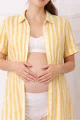 Camisa maternal de manga corta con diseño holgado, confeccionada en viscosa suave. Presenta un estampado de cuadros grandes en color rojo y crema, cierre frontal con botones y bolsillos laterales.