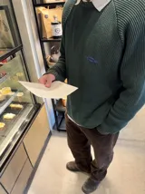 Buzo de punto acanalado negro con mangas raglán, cuello redondo y detalle de parche bordado en el pecho.