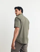 Camisa sport de manga corta, confeccionada en una mezcla de lino y algodón. Presenta cuello clásico, cierre frontal con botones de coco y un bolsillo aplicado en el pecho.