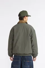 Campera Quiksilver modelo Milo para hombre, de color verde con textura en relieve y cuello camisero en contraste de color tostado. Cuenta con cierre frontal entero, bolsillos laterales ribeteados, puños y dobladillo inferior elásticos.