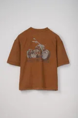 Remera de manga corta confeccionada en tejido french terry color marrón, con corte holgado y estampa frontal de una motocicleta con la palabra 'MOTORCYCLE'.