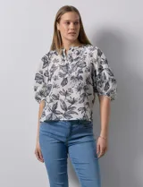 Blusa de gasa blanca con estampado de hojas en azul marino, cuello a la base con escote en V y botones, y mangas cortas abullonadas.