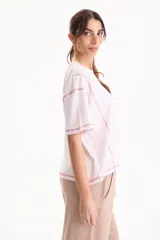 Remera de algodón blanca de manga corta y corte semi boxy, con costuras a contratono en color rosado, detalles de cortes y bordado de estrella de mar en el frente.