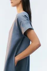 Vestido midi evasé color azul, confeccionado en lino, con escote redondo, mangas cortas con dobladillo vuelto y bolsillos laterales. Presenta un ruedo asimétrico, más largo en los laterales.