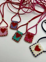 Collar con dije rectangular bordado con un corazón rojo y detalles de mostacillas de colores.