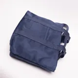 Bolso tipo tote bag de nylon azul marino, con asas de cinta tejida y bolsillo frontal exterior.