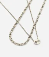 Kit de dos collares masculinos de metal con acabado plateado. El conjunto incluye una cadena de eslabones ovalados y una cadena fina con un pequeño dije central, diseñados para usar en superposición.