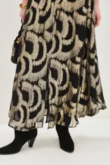 Falda midi con estampado geométrico en tonos negro y dorado metalizado. Presenta una cintura elástica fruncida y un corte fluido con caída suave.