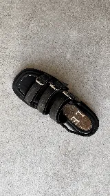 Sandalias de cuero negro con punta semicuadrada, taco cuadrado bajo y tres tiras frontales con hebillas metálicas plateadas. Cuentan con tira trasera con cierre ajustable.
