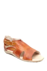 Sandalia baja de cuero en tono mostaza con detalles en cuero marrón, diseño de aberturas laterales y cierre con hebilla metálica ajustable en el tobillo.